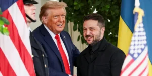 Володимир Зеленський посміхається поруч з Дональдом Трампом біля прапорів США та України