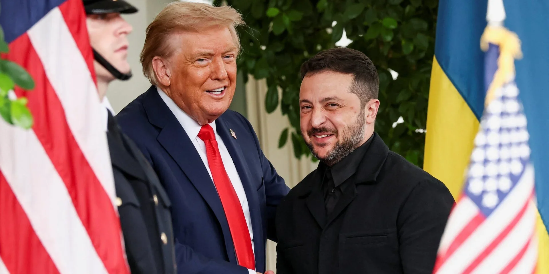 Володимир Зеленський посміхається поруч з Дональдом Трампом біля прапорів США та України