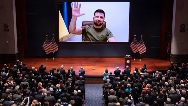 Володимир Зеленський на екрані махає рукою перед аудиторією США щодо доказів РФ-Ірану
