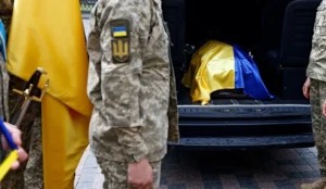 Українські військові біля фургона з труною загиблого воїна під прапором під час репатріації 1000 тіл