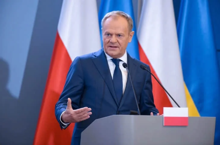 Дональд Туск выступает по поводу кризиса в НАТО и мечты Путина на фоне флагов Польши и Украины