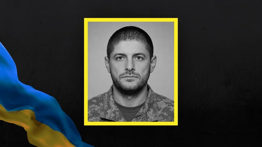 Роман Шамота у військовому камуфляжі на тлі прапора України