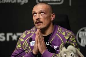 Олександр Усик зі складеними руками біля іграшки Акели на пресконференції