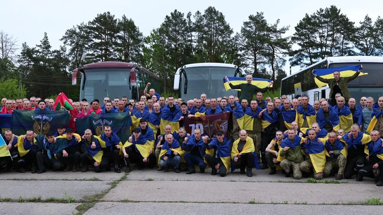 Звільнені з полону азовці та українські воїни біля автобусів з прапорами