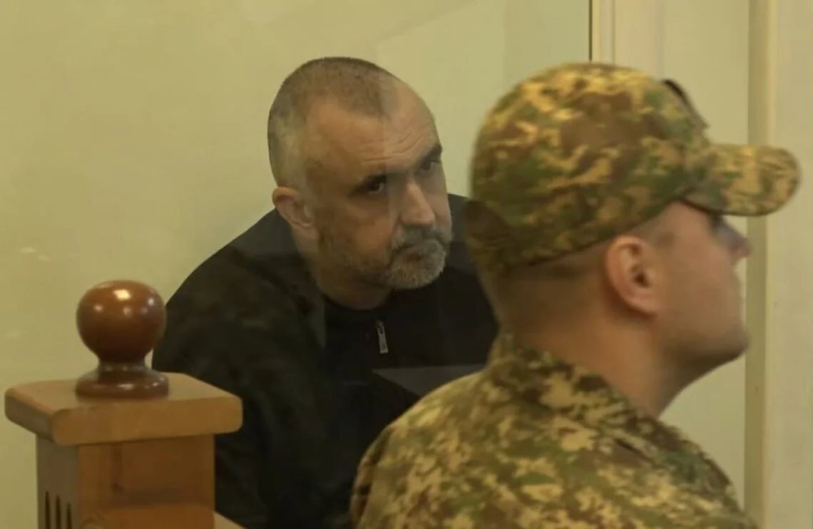 Пленный Антон Милаев под наблюдением украинского военного в камуфляже