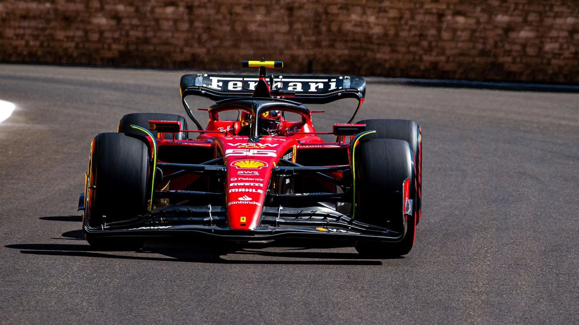 Червоний болід Ferrari з номером 55 їде трасою перед цегляною стіною