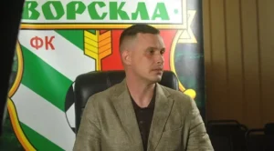 Чоловік у бежевому піджаку сидить перед банером ФК Ворскла